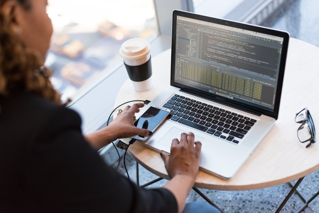 A person sitting at a table with a laptop and a phone.