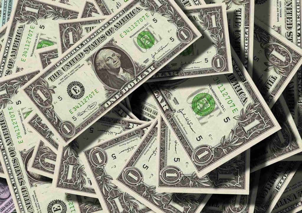 A scattered pile of US one-dollar bills, reminiscent of equitable compensation allowed for breach of an arbitration clause by a third party. The notes, featuring the portrait of George Washington, are overlapping each other and slightly crumpled, creating a textured surface with varying shades of green and white.
