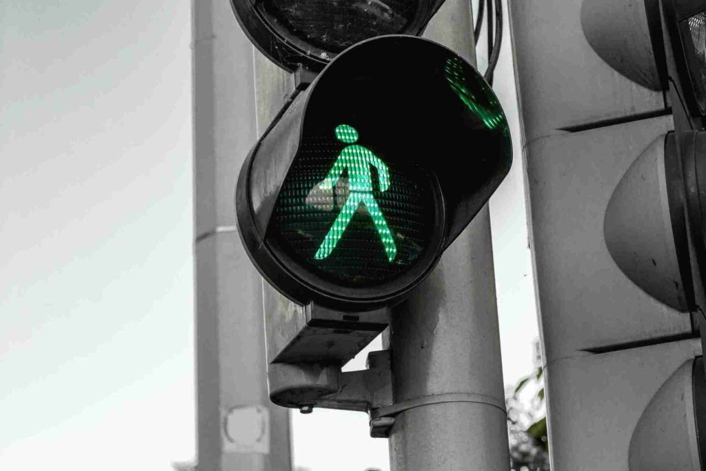 A close-up photo of a green pedestrian traffic light showing a walking person symbol. The background is slightly blurred, highlighting the signal. The greyish tones in the surroundings contrast with the illuminated green light, resembling how The Trusts Act 2019 brings clarity and focus, keeping it in the family.